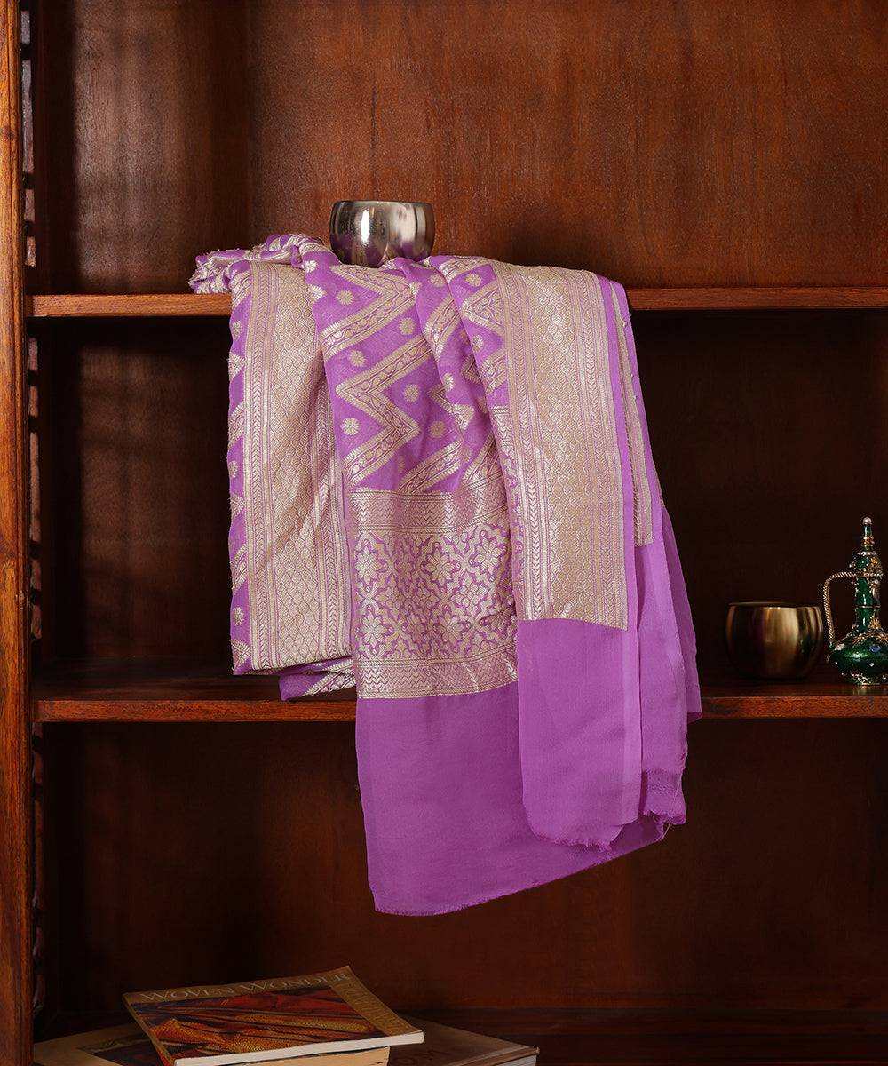 Lavender handloom georgette dupatta draped over a wooden cabinet, showing its chevron cutwork weave, ornate border and plain end section.