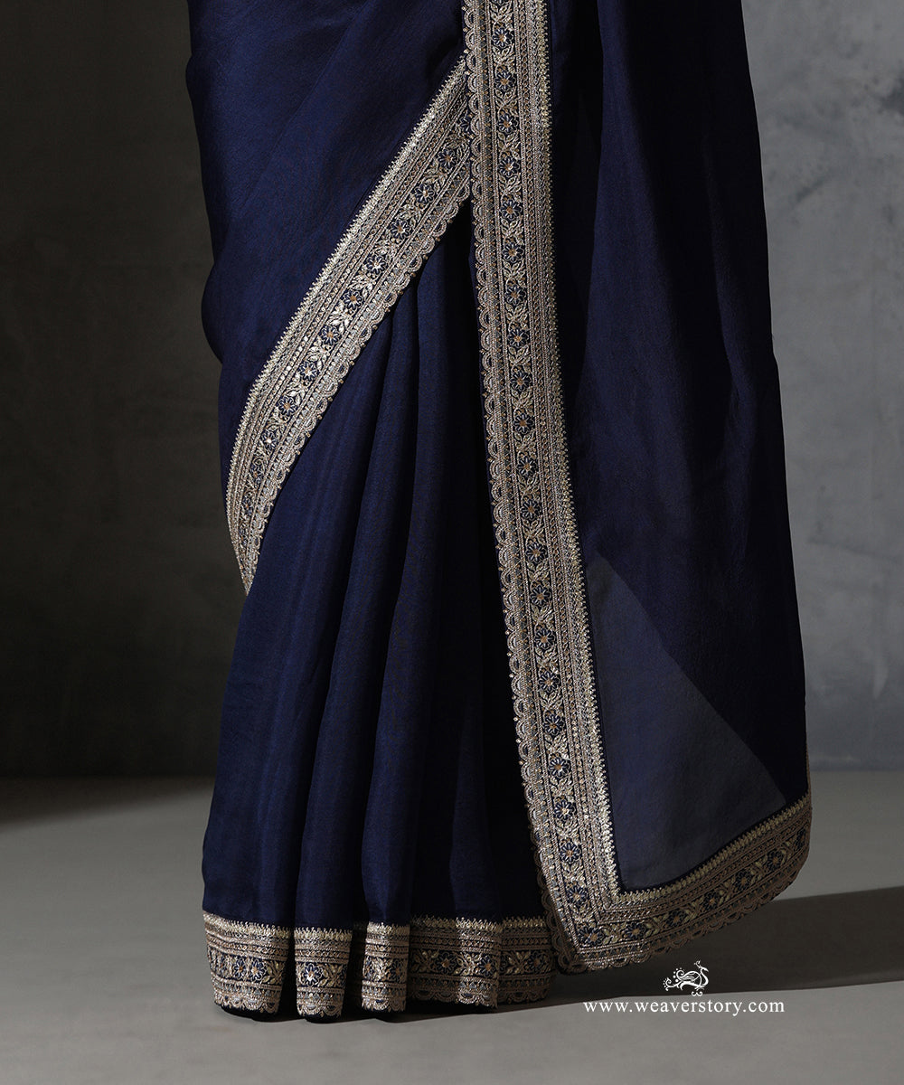 Close-up of Tarini navy blue organza saree showing the hand-operated machine embroidered floral thread and zari border with scalloped edging.