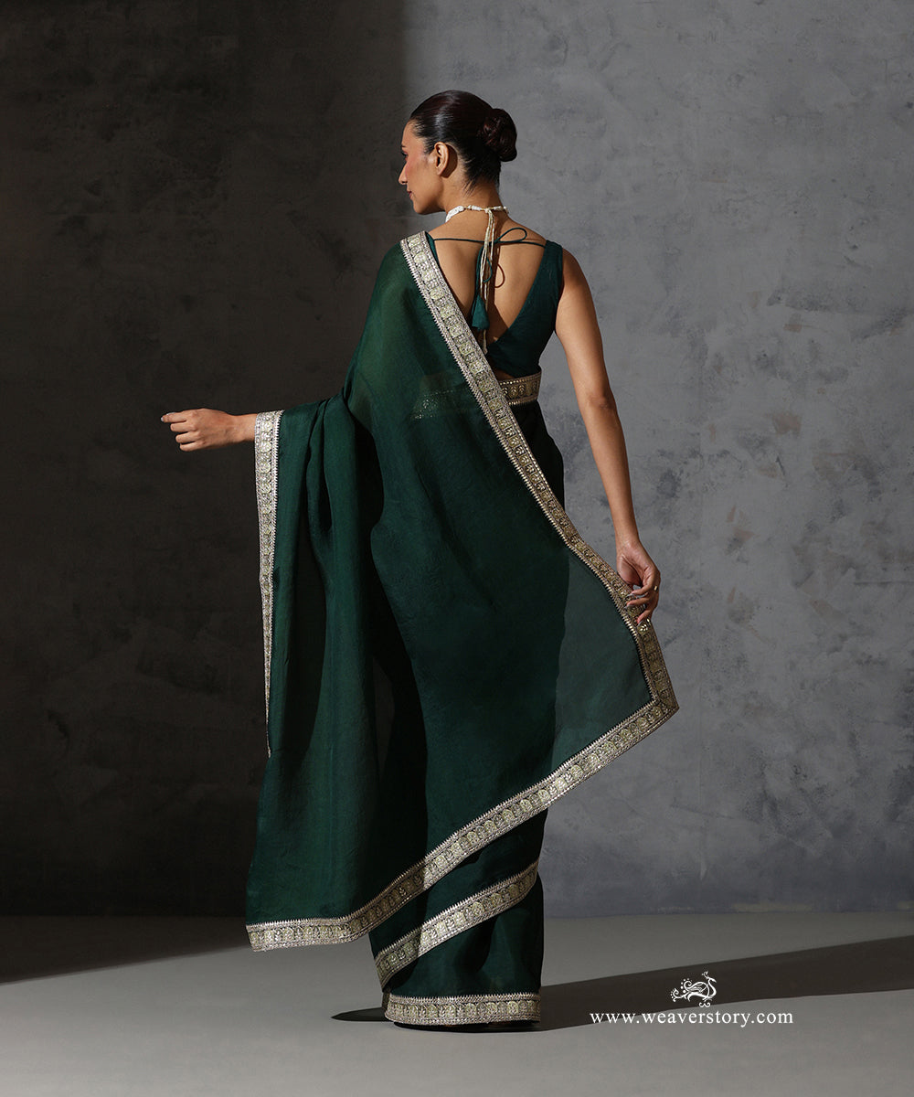 Bottle green organza silk saree from The Heirloom Vault with handcrafted resham and zari embroidered border.
