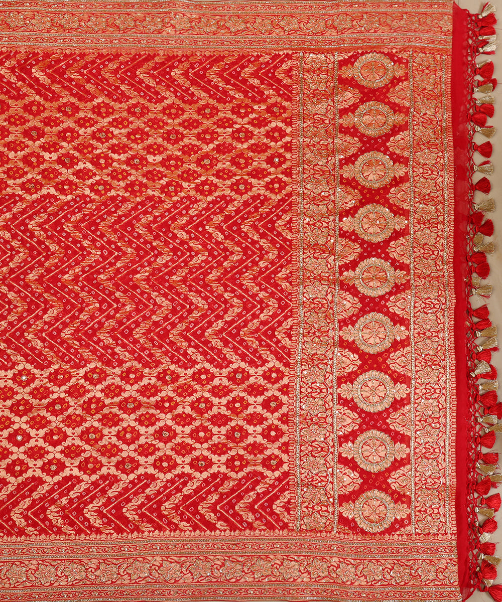 Full view of red Banarasi Bandhani dupatta with alternating chevron and floral patterns, an ornate medallion palla and tasselled edge