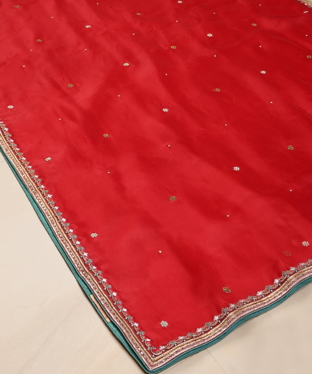 Angled view of red organza dupatta showing the finely embroidered floral-vine border, metallic detailing and green edging.