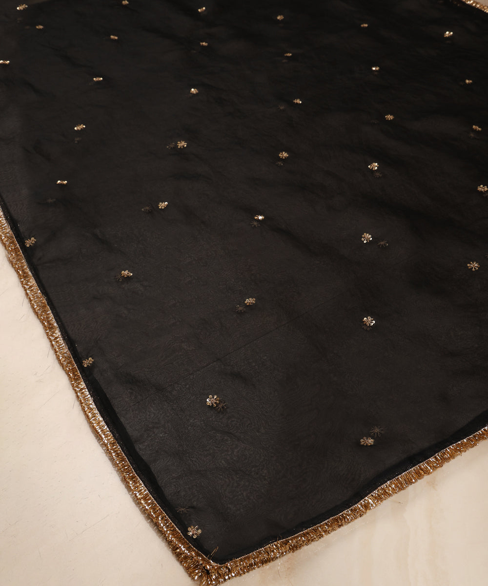 Angled view of black organza dupatta featuring evenly scattered hand-embroidered zardozi bootis and metallic edging.