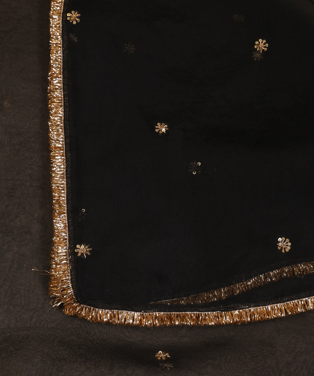Close-up of black organza dupatta with petite gold zardozi floral bootis and a slender metallic fringe border.