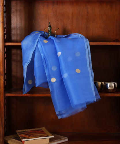 Royal blue handloom organza silk dupatta draped against a wooden cabinet, featuring gold and silver zari bootis and tonal edging.