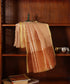 Gold handloom Kora tissue Jamdani dupatta draped over a wooden cabinet, showing the richly woven surface and softly luminous finish