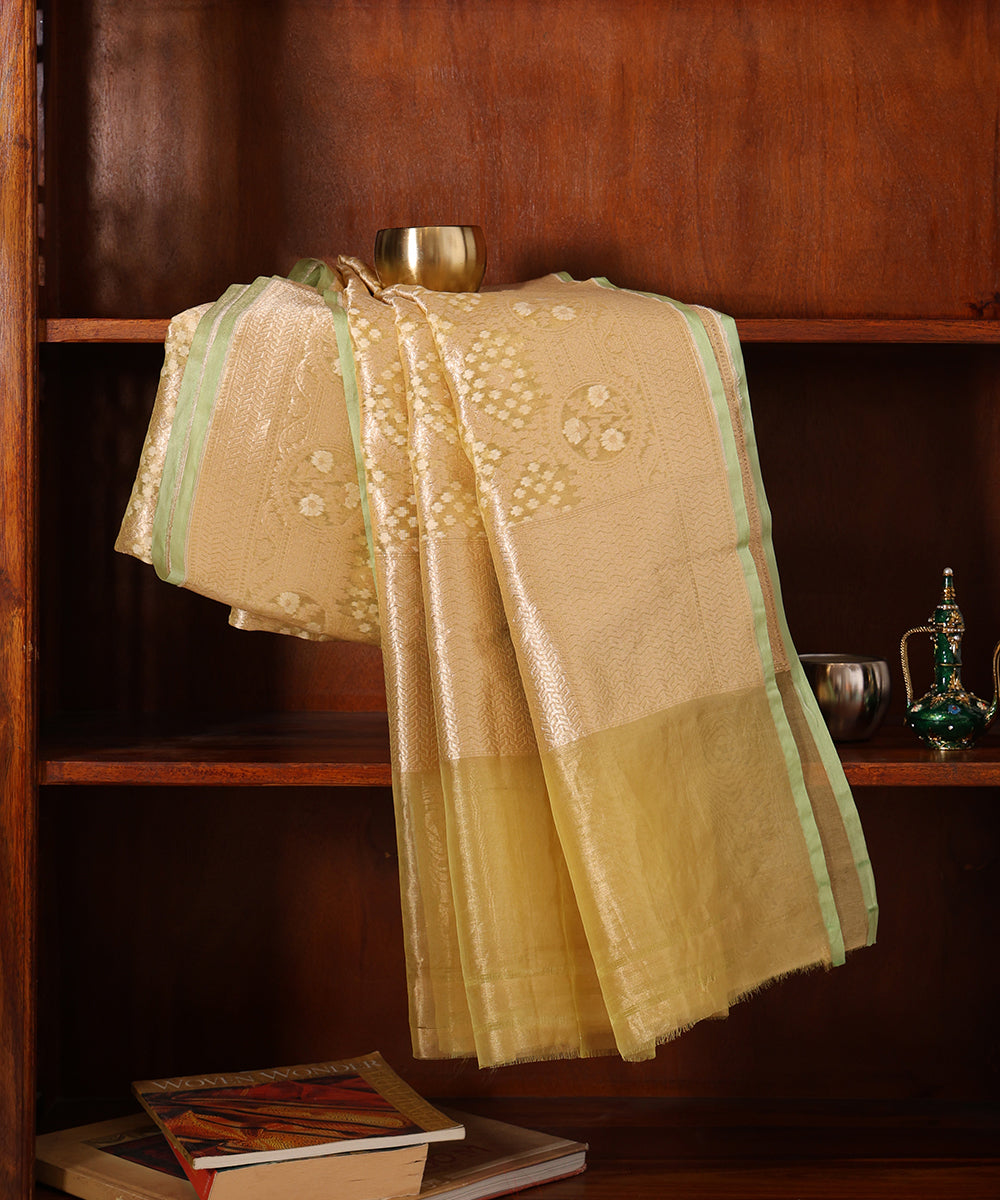 Lemon handloom Kora tissue dupatta draped over a wooden cabinet, showing its luminous patterned weave, sheer section and pale-green edging.