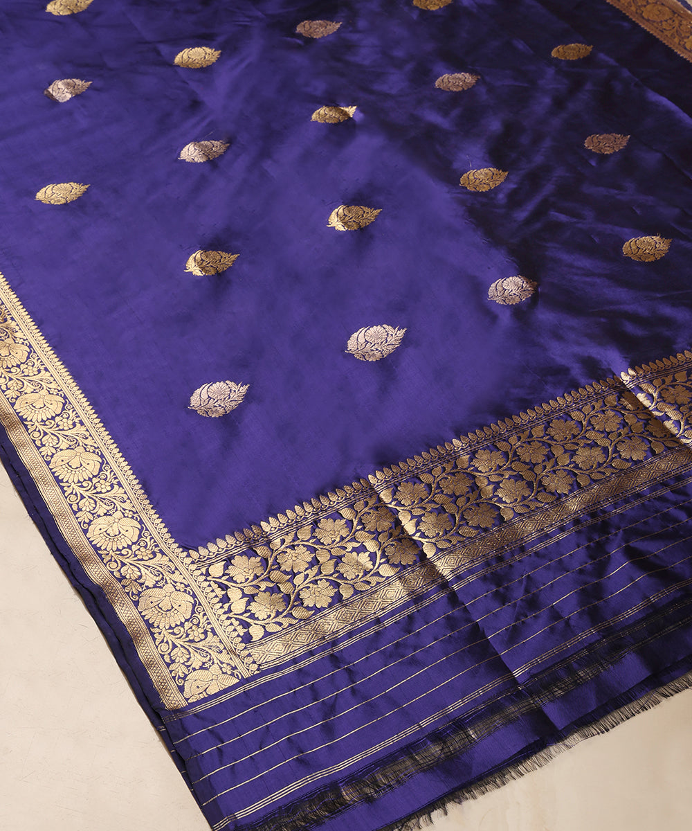 Full view of blue pure Katan silk Banarasi dupatta with gold zari leaf bootis, an ornate floral border and striped palla.
