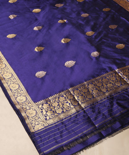 Full view of blue pure Katan silk Banarasi dupatta with gold zari leaf bootis, an ornate floral border and striped palla.