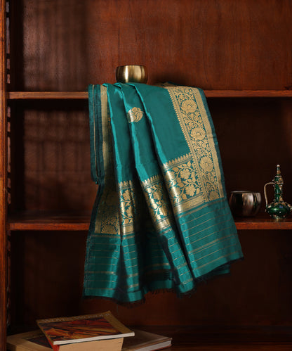 Green pure Katan silk Kadhwa dupatta displayed against a wooden cabinet, showing gold zari bootis, floral borders and fine palla stripes.
