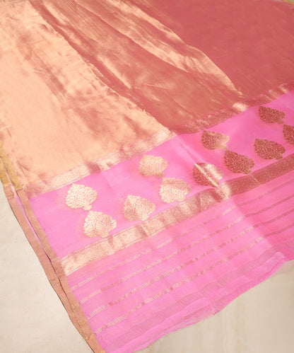 Pink and gold Banarasi Kora tissue dupatta displayed against a wooden cabinet, showing floral bootas, zari stripes and sheer texture.