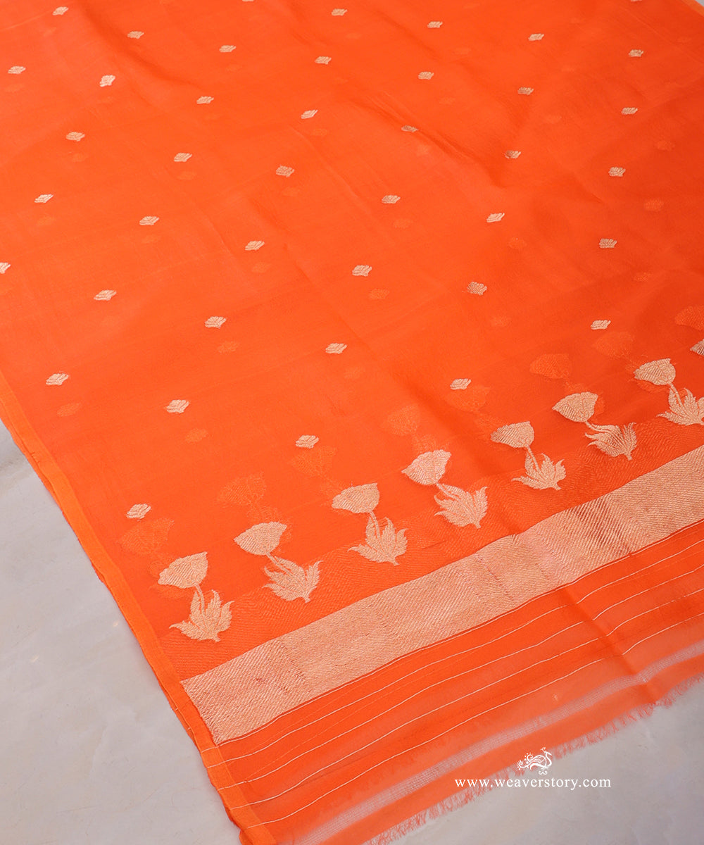 Orange Kora silk dupatta showing scattered floral bootis, a row of lotus blooms with leafy stems and a gold-toned chevron end panel.