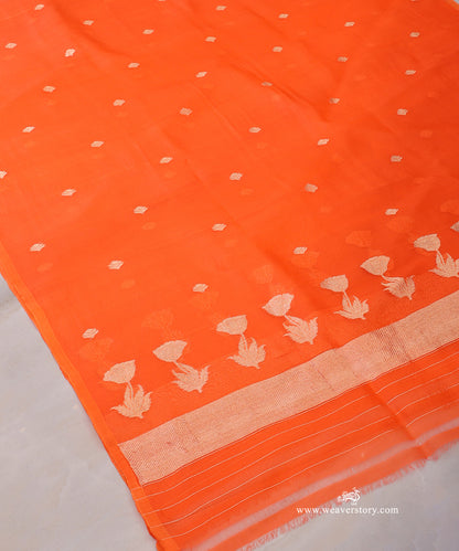 Orange Kora silk dupatta showing scattered floral bootis, a row of lotus blooms with leafy stems and a gold-toned chevron end panel.