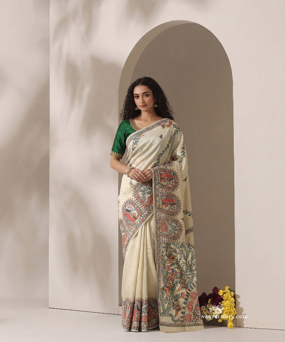 Model wearing a cream handloom Chanderi saree with intricate Madhubani fish and bird painting.