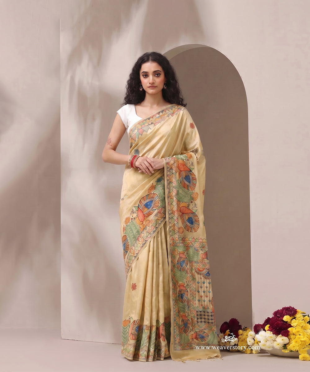 Model wearing a beige gold handloom Chanderi Madhubani saree with intricate painted bird borders.