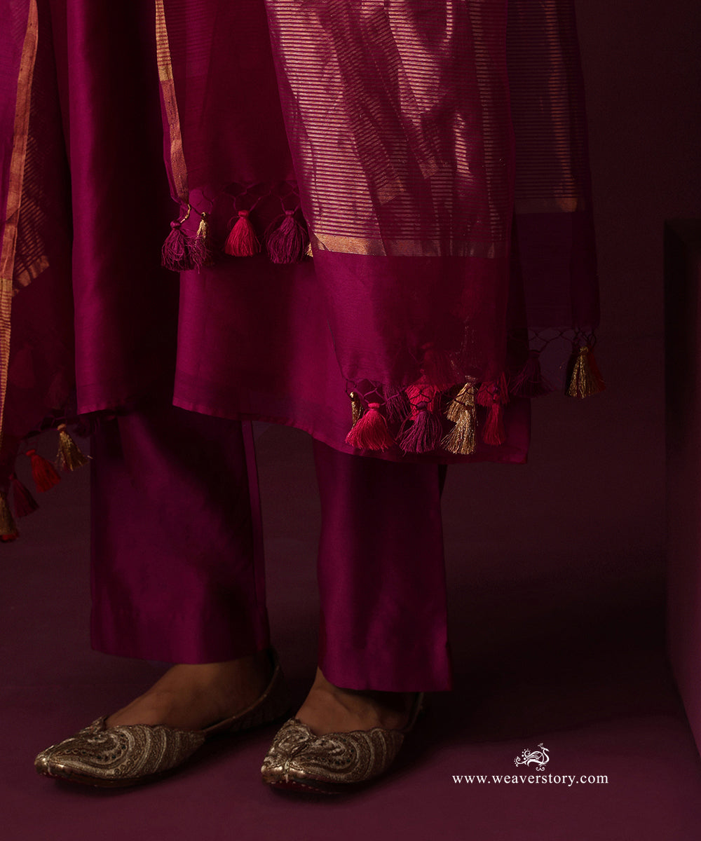 Detail of the deep magenta dupatta’s striped gold border and tassels with matching straight pants