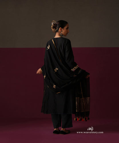 Back view of the black suit with scattered floral motifs on the dupatta and a striped gold border