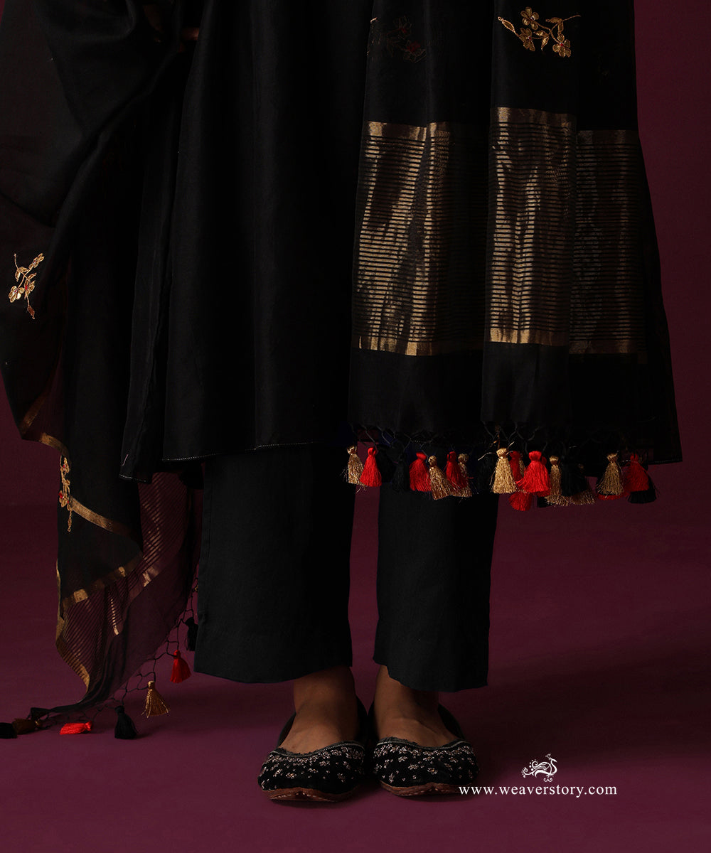 Detail of the black straight pants, striped gold dupatta border and red, black and gold tassels