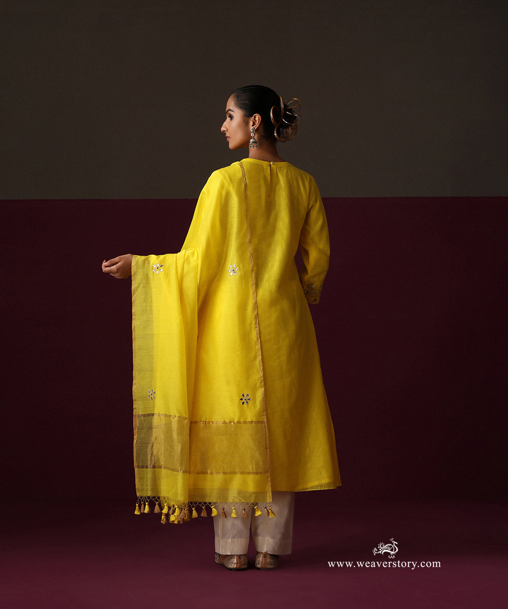 Back view of the yellow kurta and dupatta with spaced floral bootas, gold tissue border and tassels