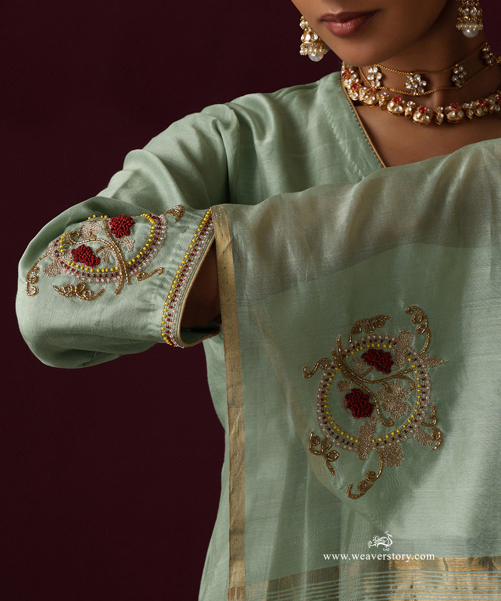 Close-up of red and gold-toned zardozi embroidery on the sage green sleeve cuff and dupatta