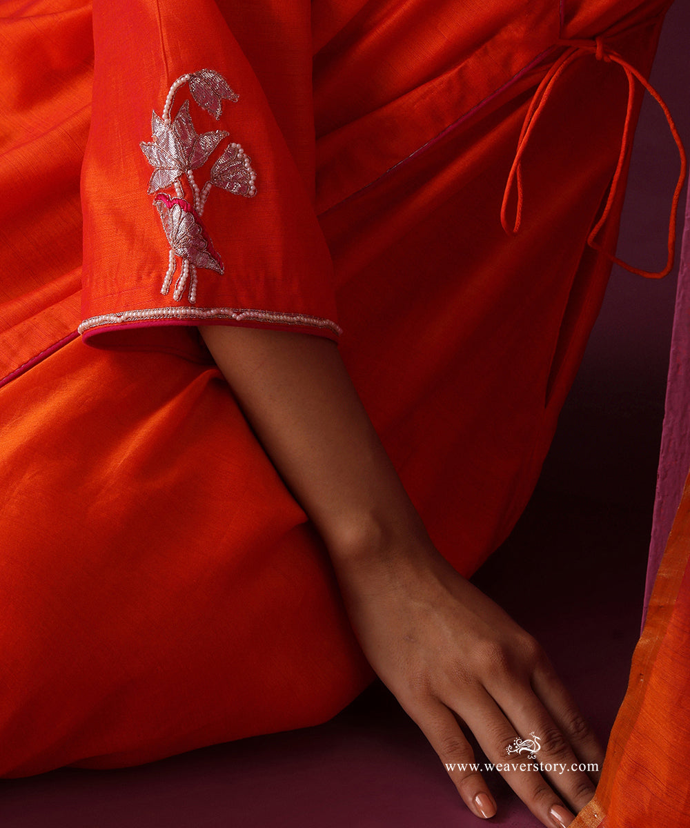Close-up of the Angrakha waist tie and lotus bud embroidery on the orange sleeve cuff
