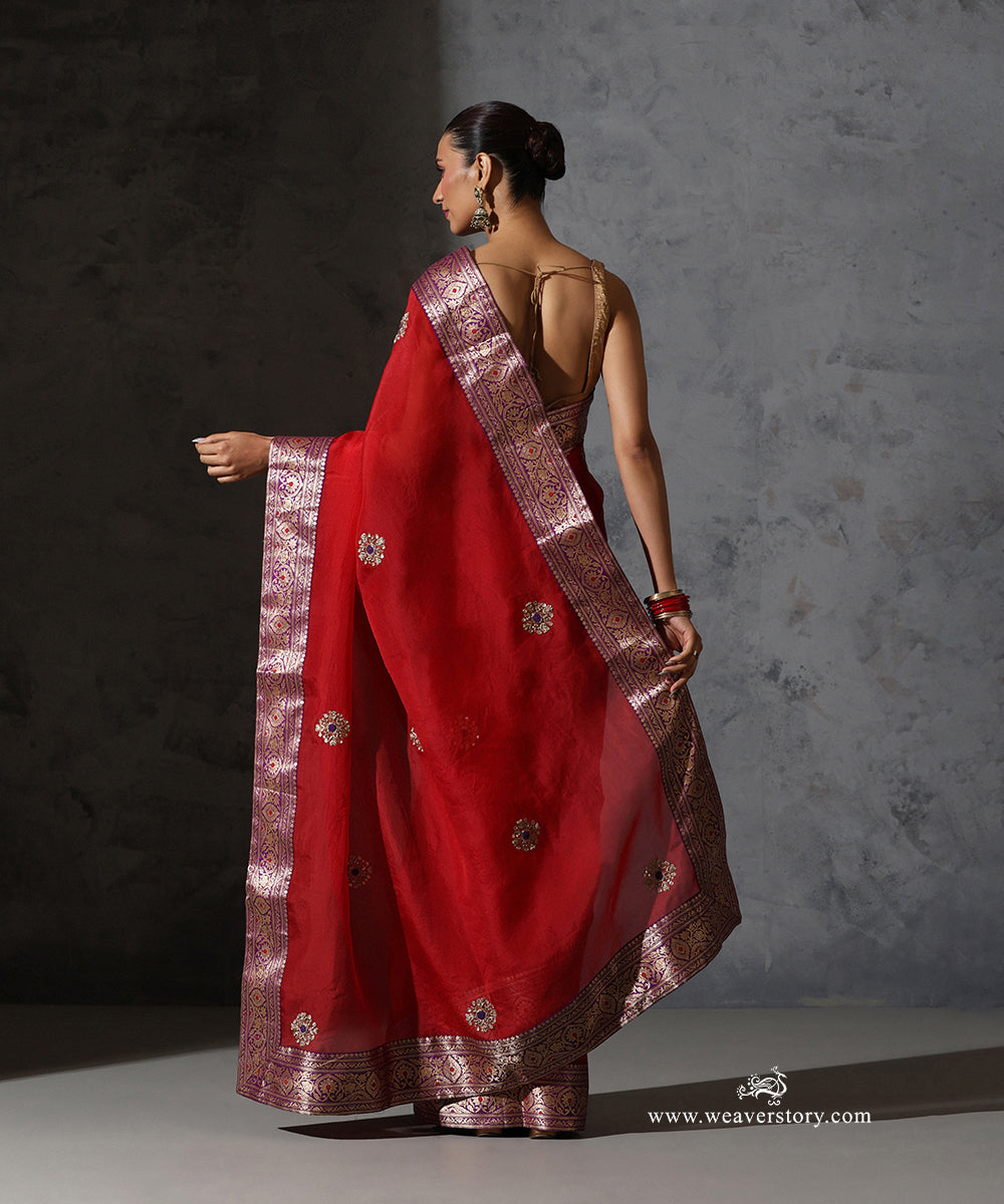 Back drape of Kaushiki red organza saree showing hand-embroidered meenakari bootis and contrast purple Banarasi zari border.