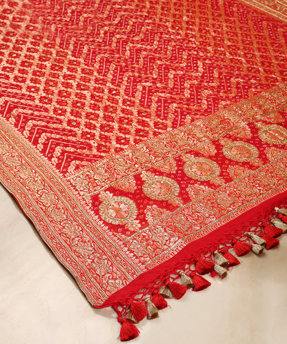 Detailed view of red Bandhani dupatta featuring chevron Bandhej patterns, circular palla motifs and intricate floral borders.