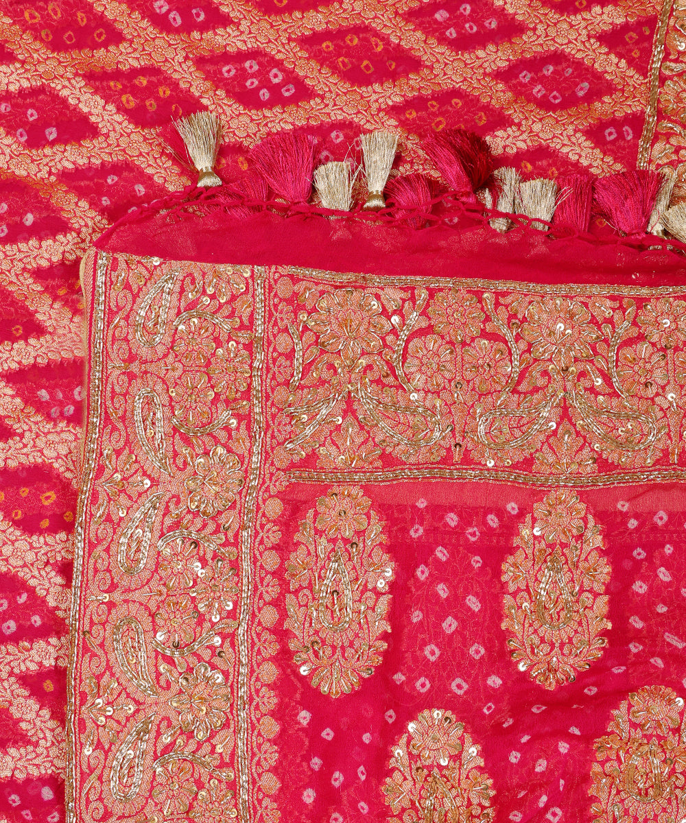 Close-up of hot pink Khaddi georgette Bandhani dupatta with ornate paisley borders, zardozi highlights and pink-and-gold tassels