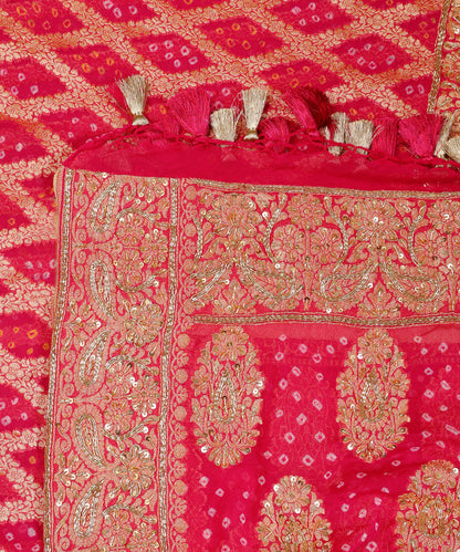 Close-up of hot pink Khaddi georgette Bandhani dupatta with ornate paisley borders, zardozi highlights and pink-and-gold tassels