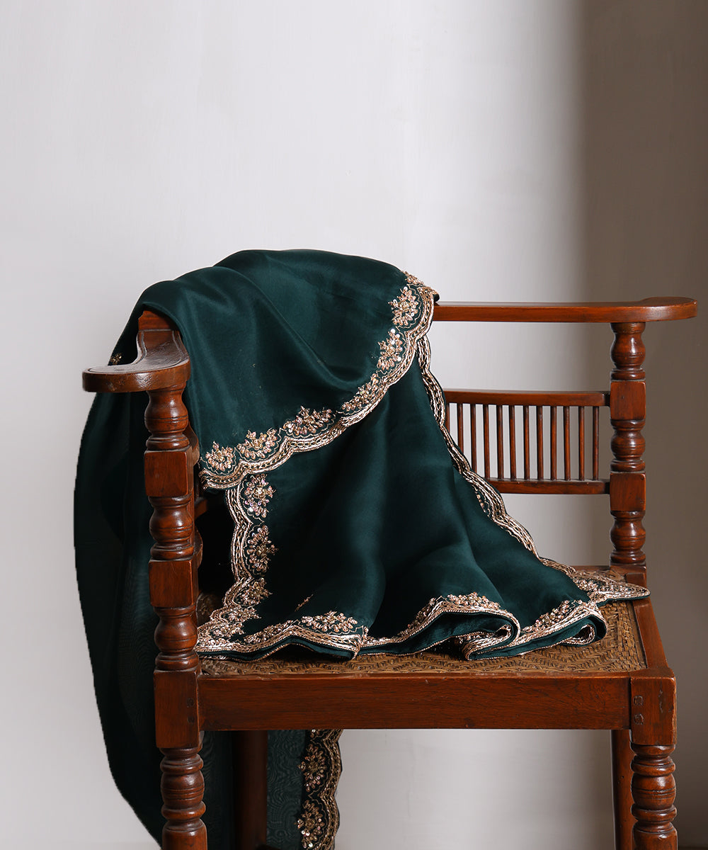 Dark bottle green handloom organza dupatta draped over a wooden chair, showing its rich colour and intricate metallic zardozi border.