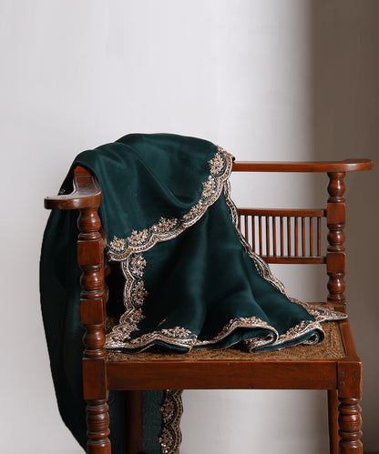Dark bottle green handloom organza dupatta draped over a wooden chair, showing its rich colour and intricate metallic zardozi border.