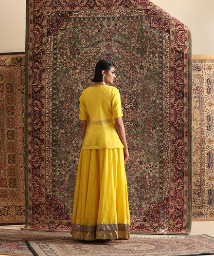 Back view of yellow Chanderi silk lehenga set with organza overlay top and handcrafted antique gold lampi gota border