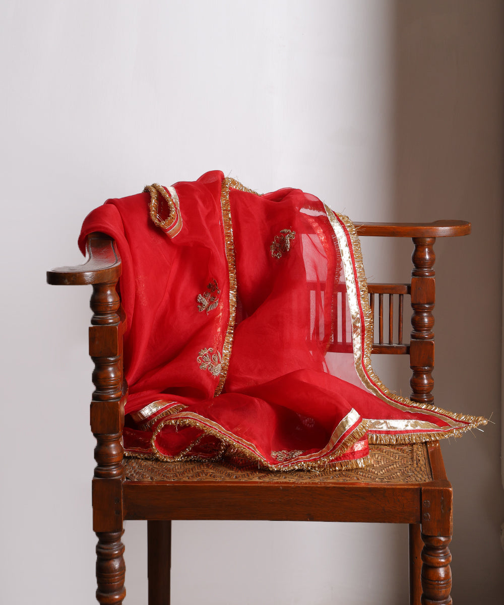 Close-up of red organza dupatta with hand-embroidered zardozi farisha bootas, gleaming gota and metallic kiran edging.