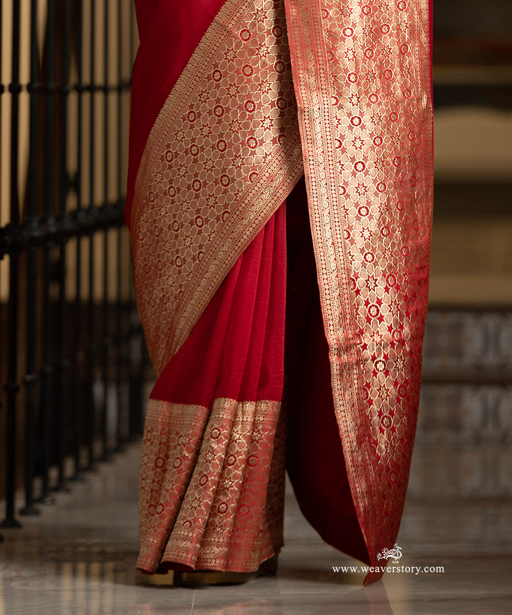Red saree with gold embroidery draped over a chair, brand &