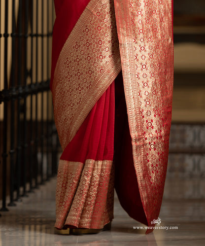 Red saree with gold embroidery draped over a chair, brand &