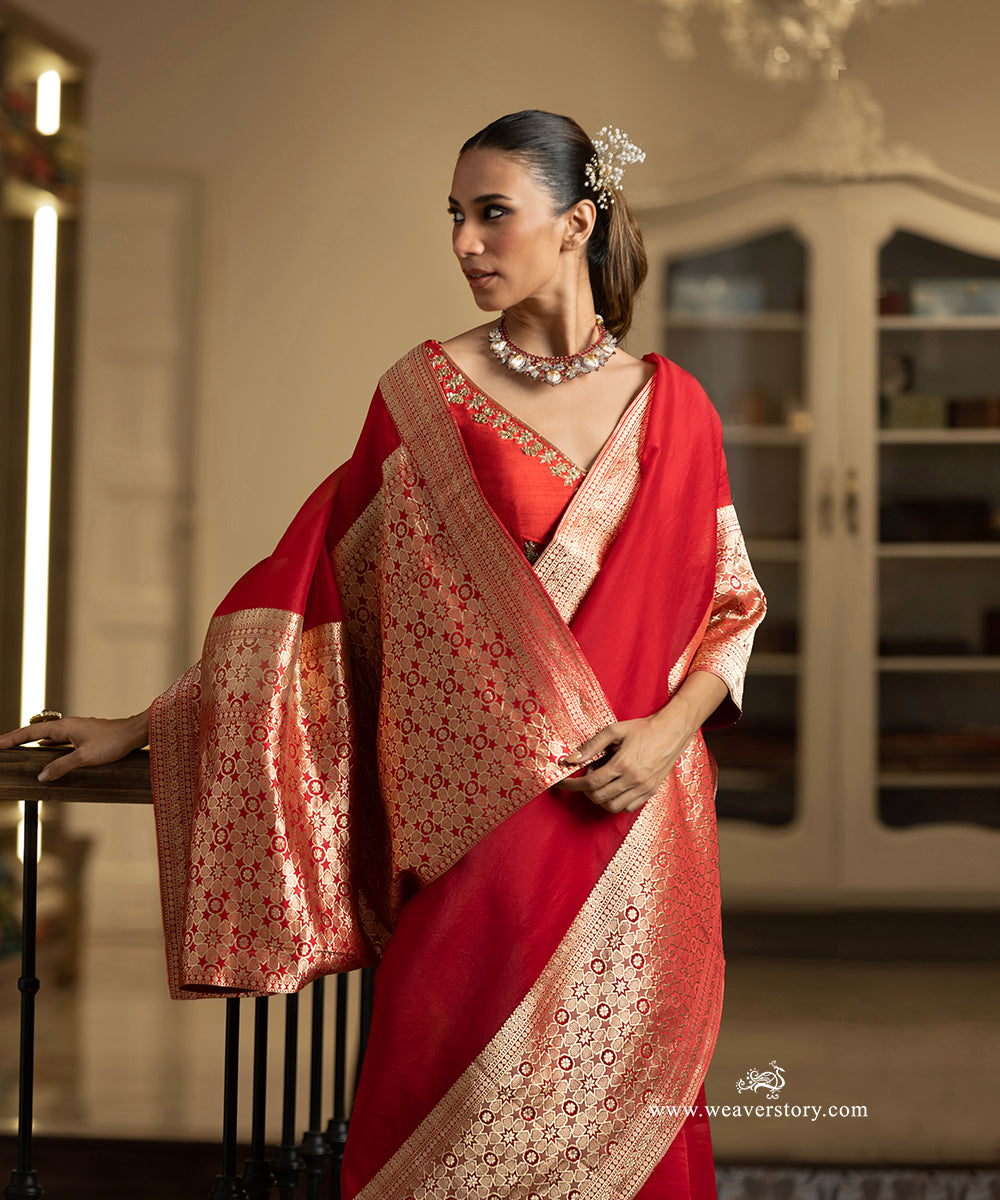 Woman wearing a red saree with gold patterns indoors