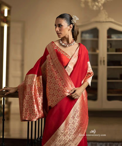 Woman wearing a red saree with gold patterns indoors